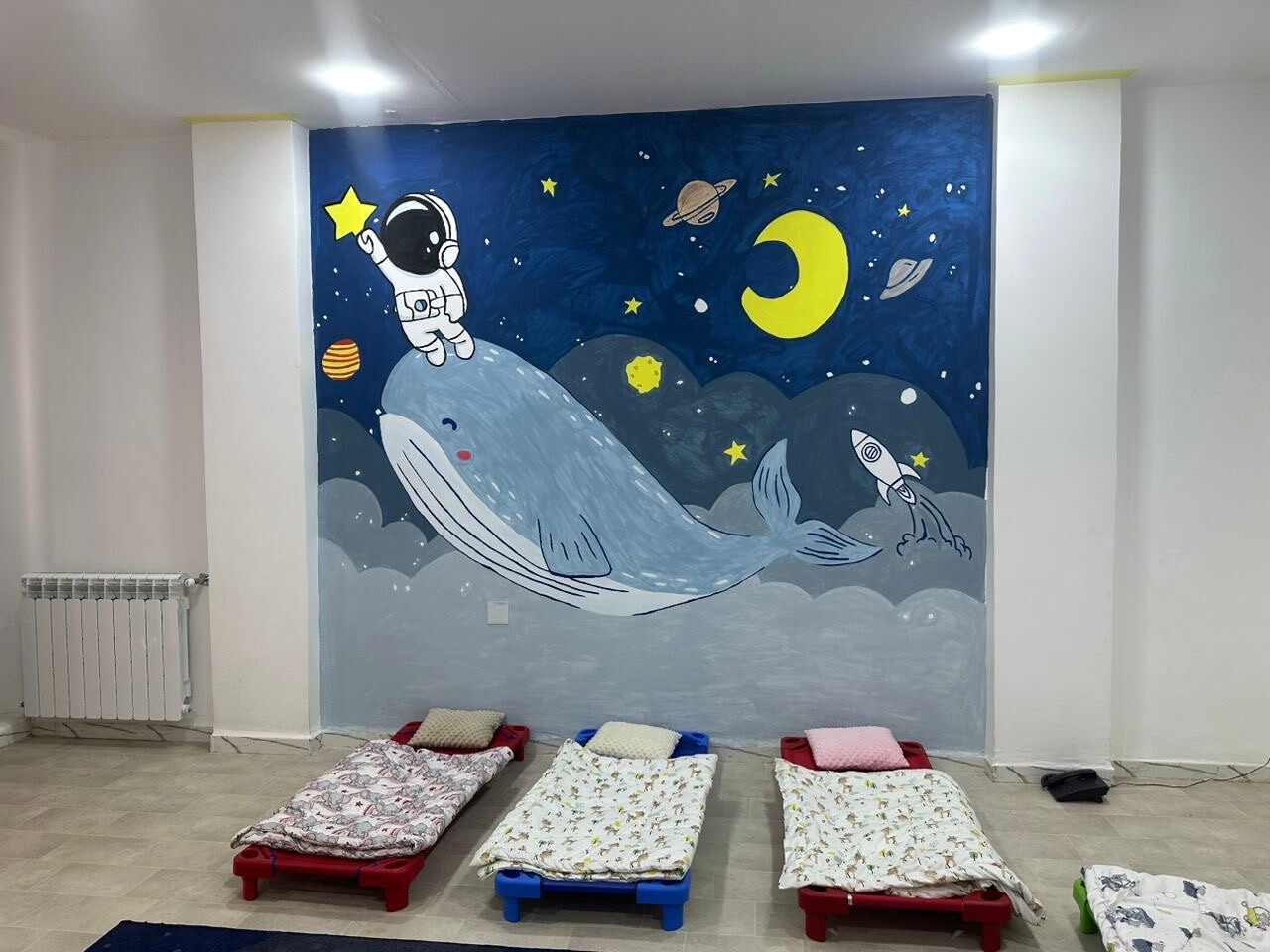 Espace de repos avec petits lits et fresque sur le thème de l’espace